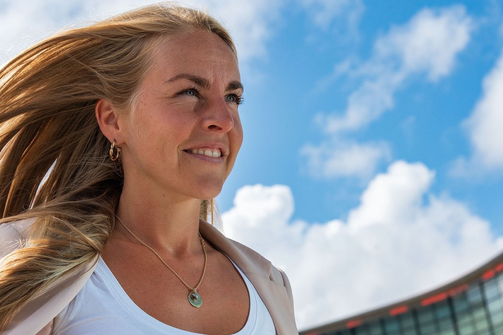 Kvinne med halssmykke foran bygning