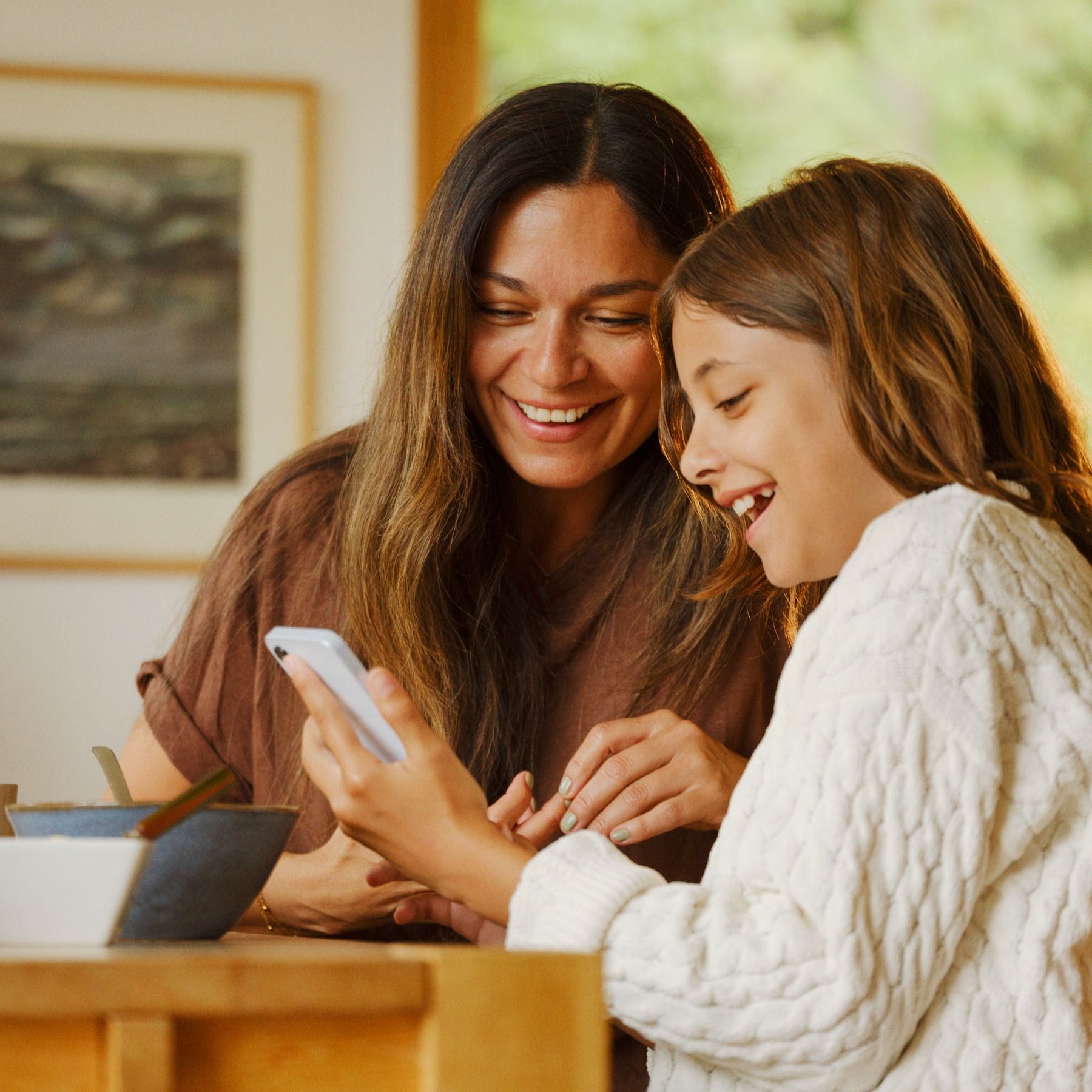 To personer i lys setting, en holder en mobiltelefon