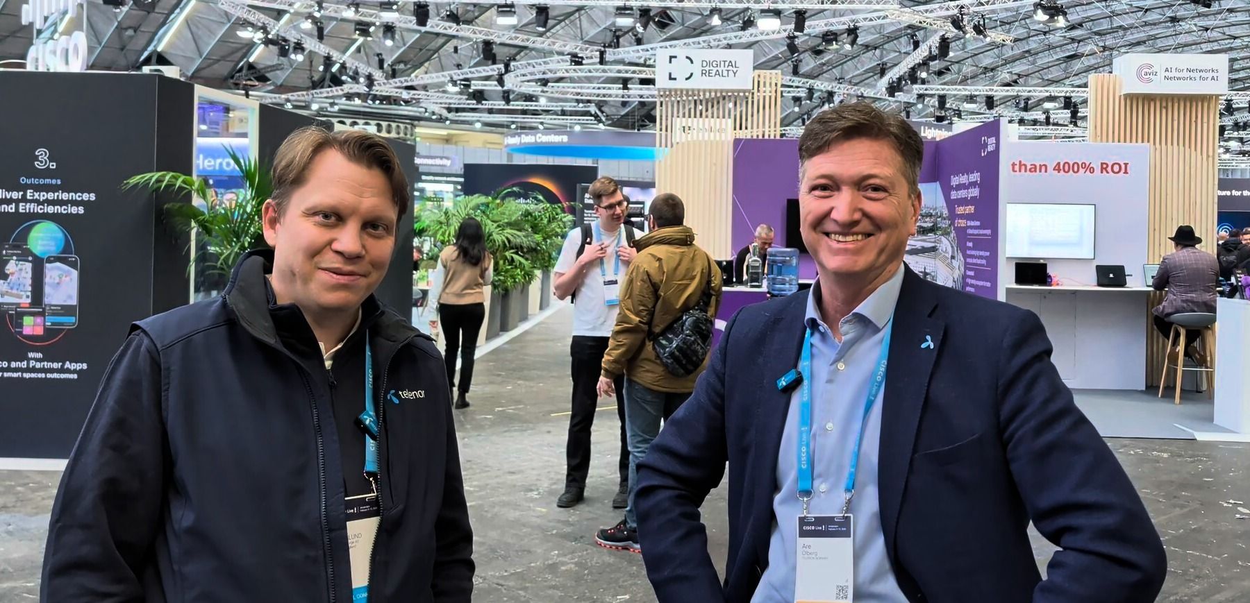 To personer på Cisco Live med flere stands i bakgrunnen