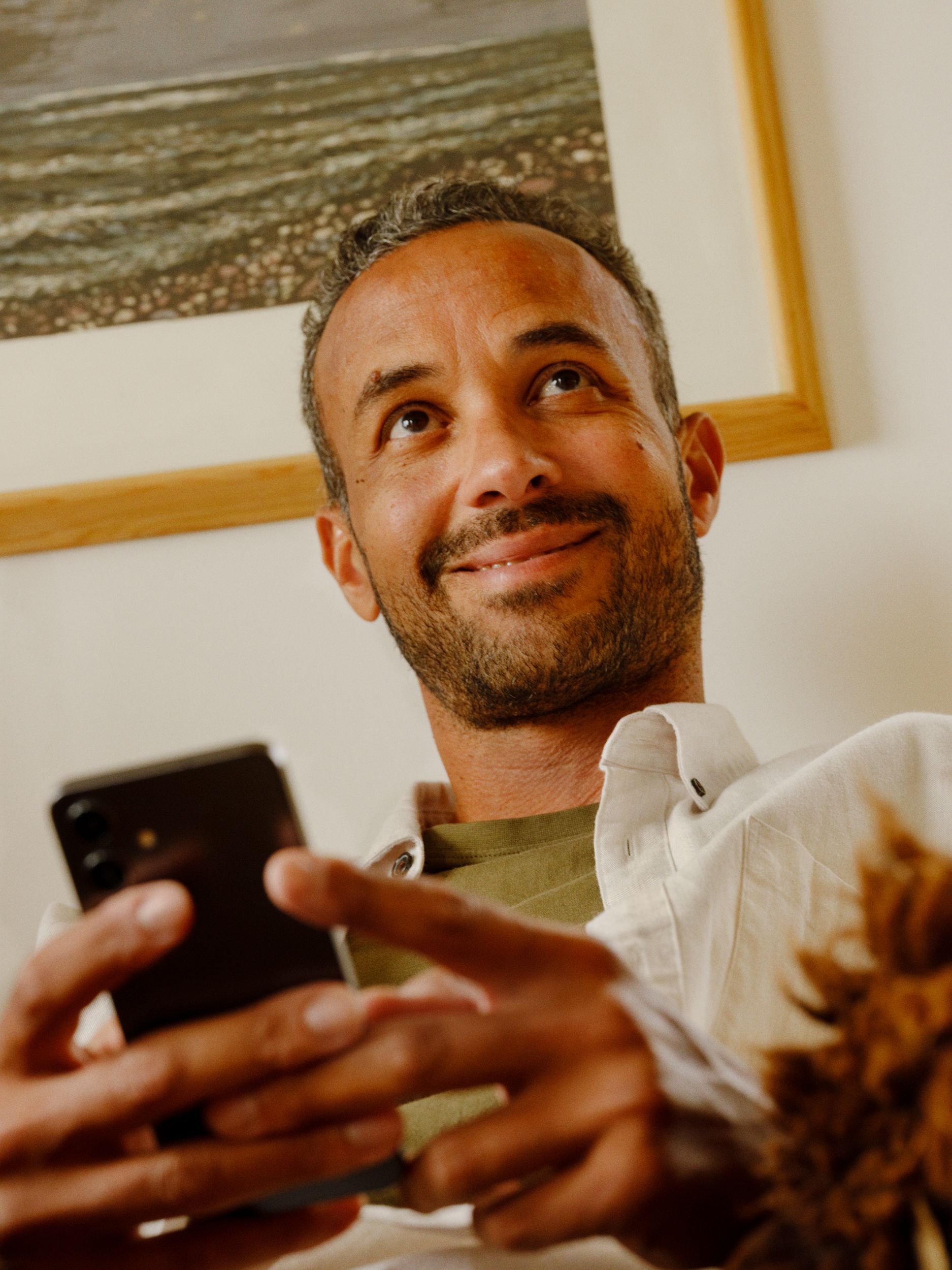 Mann som sitter med mobil i hånden