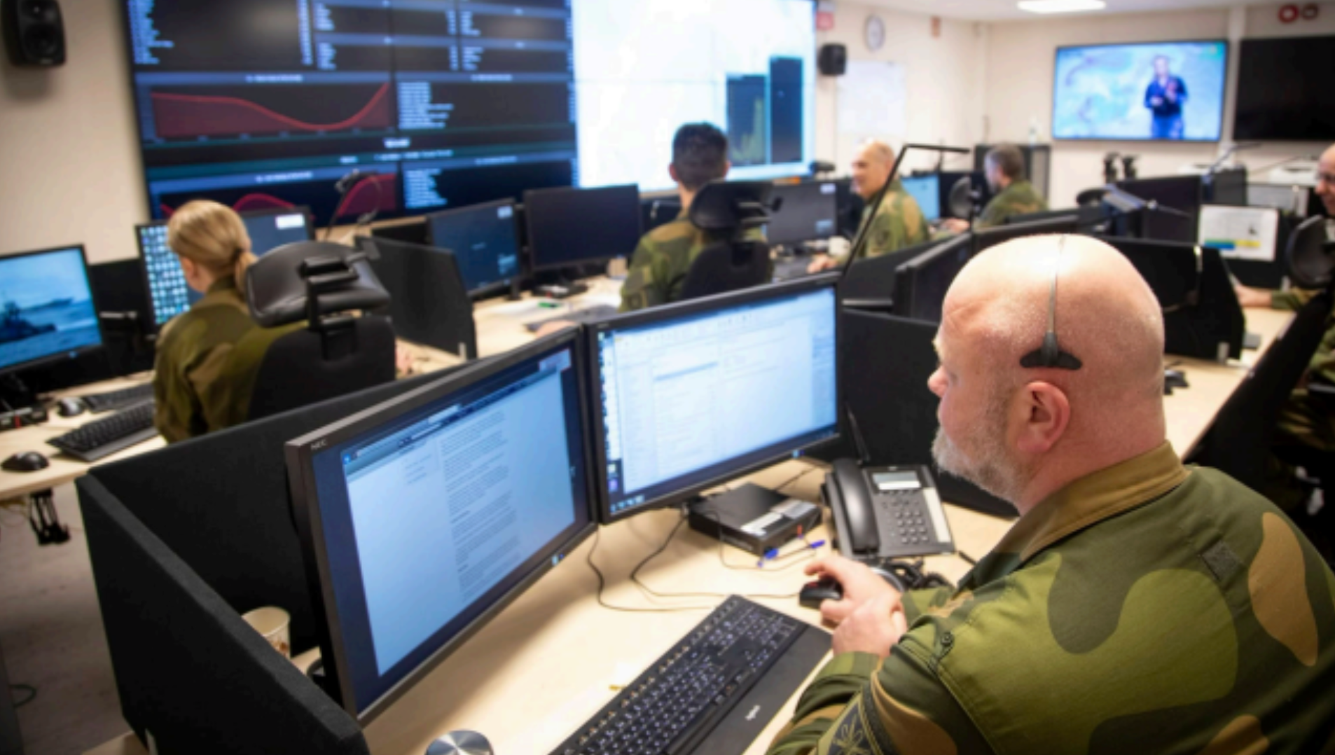 Personale i uniform jobber ved datamaskiner i et kontrollrom