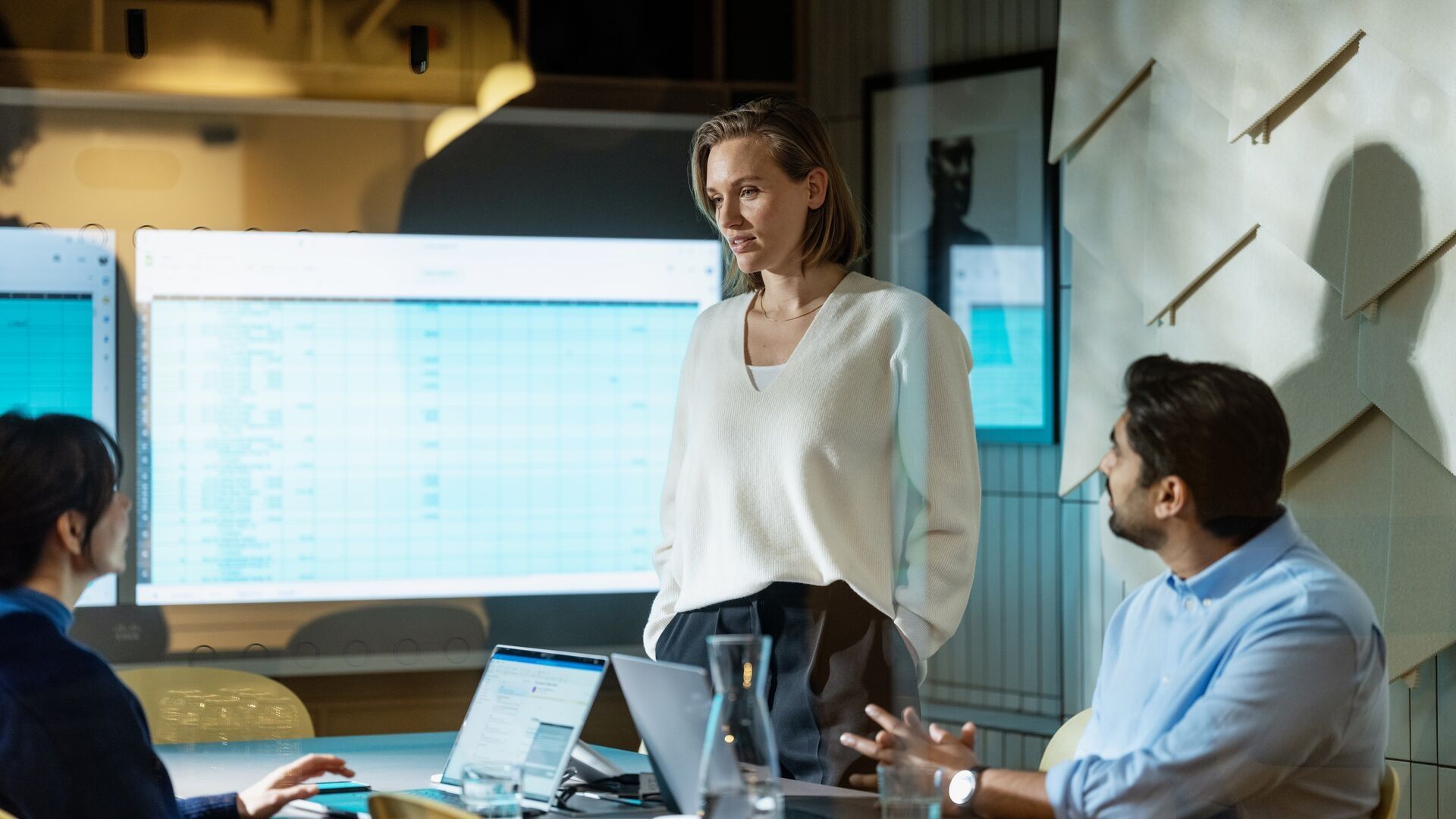 Personer i møte med skjerm som viser dataanalyse