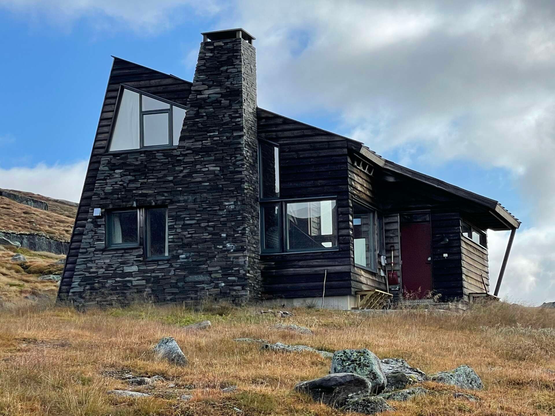 Hytte på Finse med mørkt treverk og steinpipe i fjellandskap