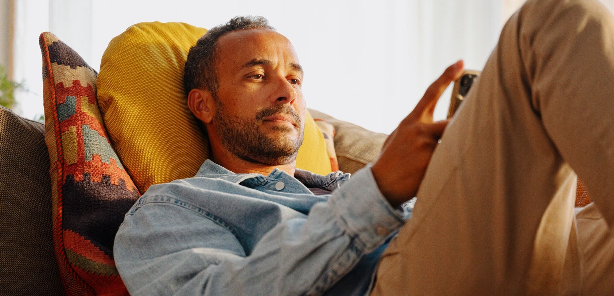 En person slapper av på en sofa med mobiltelefon i hånden