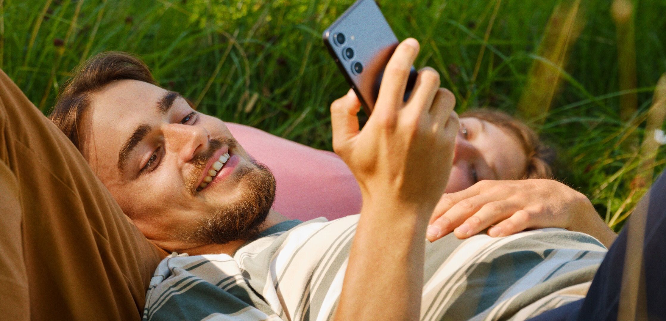 To personer i gresset, én med mobiltelefon