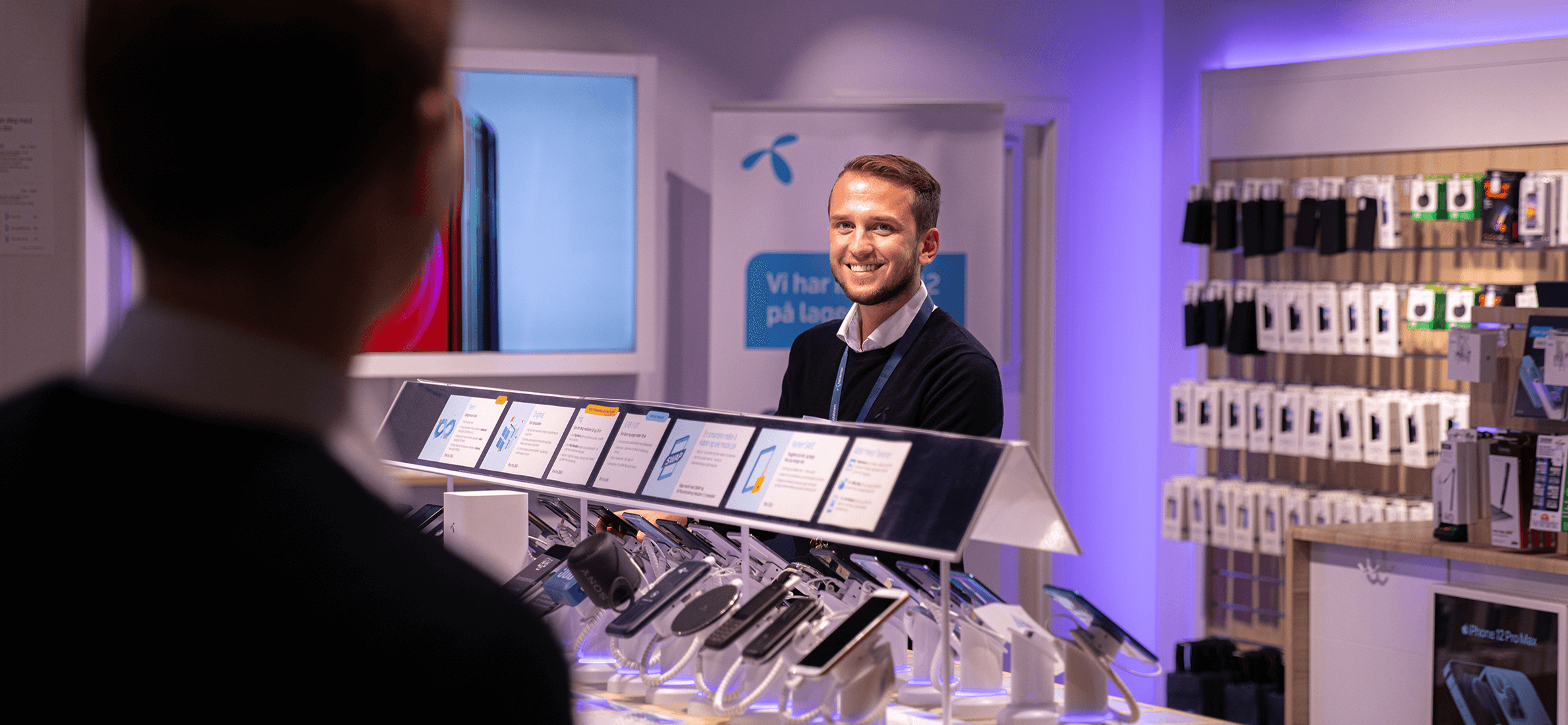 En medarbeider som jobber i Telenorbutikken Notodden smiler til kunden som kommer inn