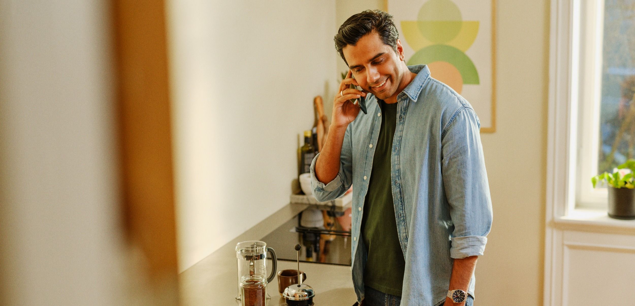 Mann som snakker i mobilen ved en kjøkkenbenk