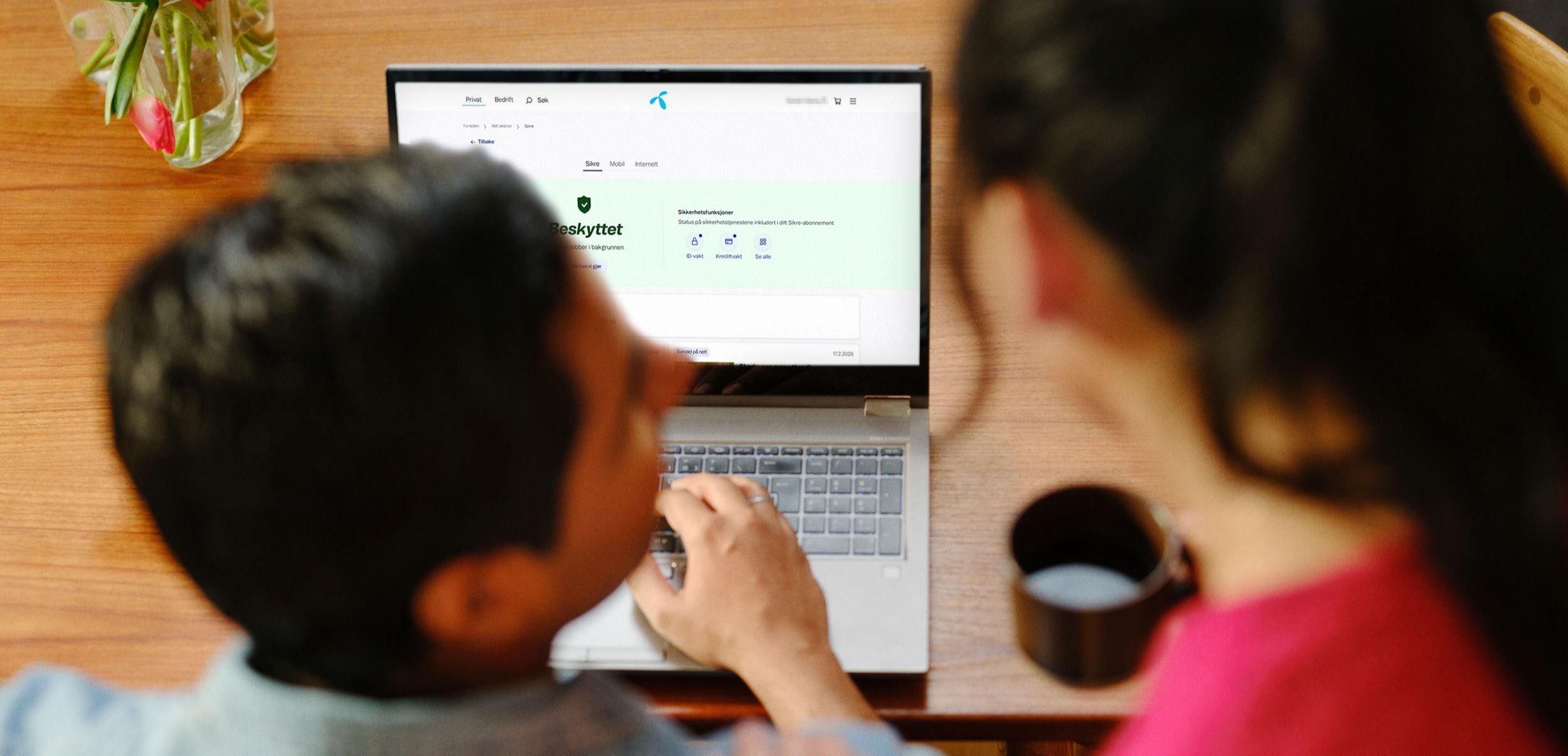 To personer ser på en bærbar PC med nettsiden "Nettslett"