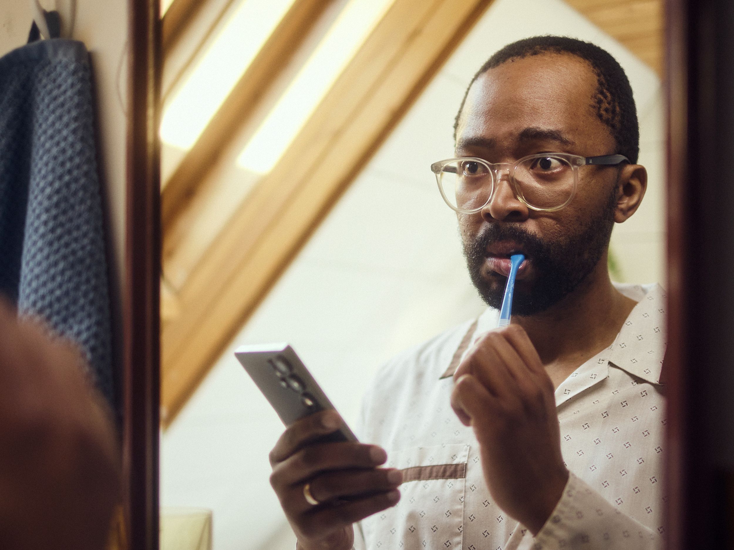 mann pusser tenner med mobil i hånda