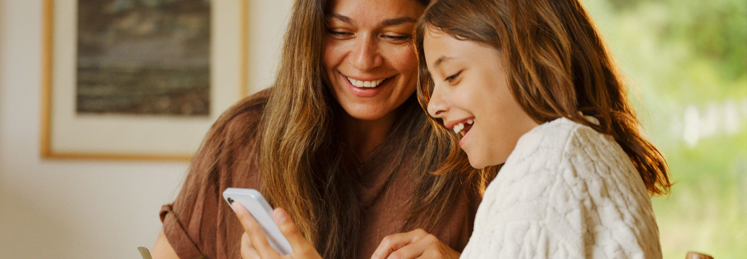 Mor og datter ser på en mobil sammen