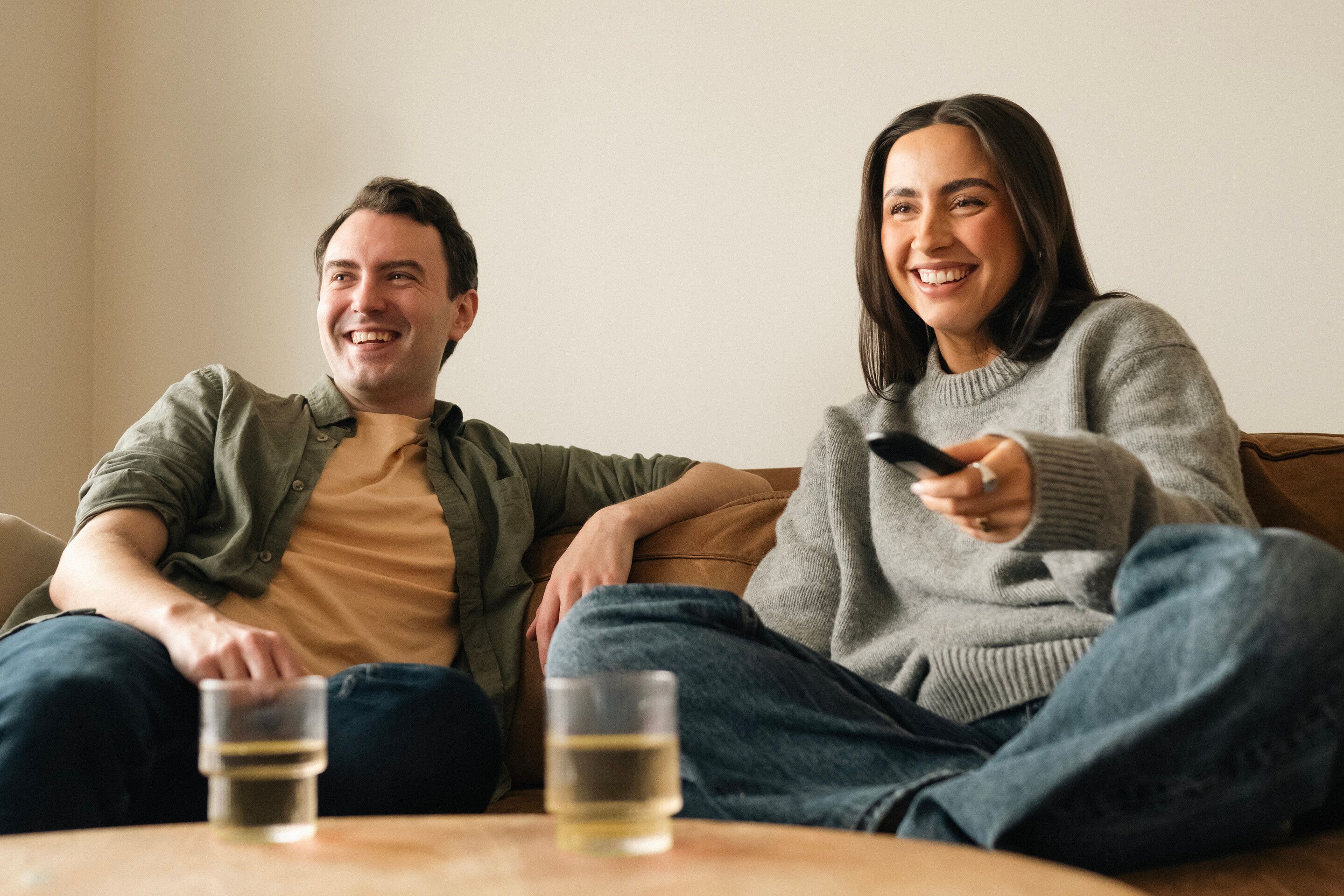 Et smilende par sitter i sofaen og ser strømmetjenester med Streamix.