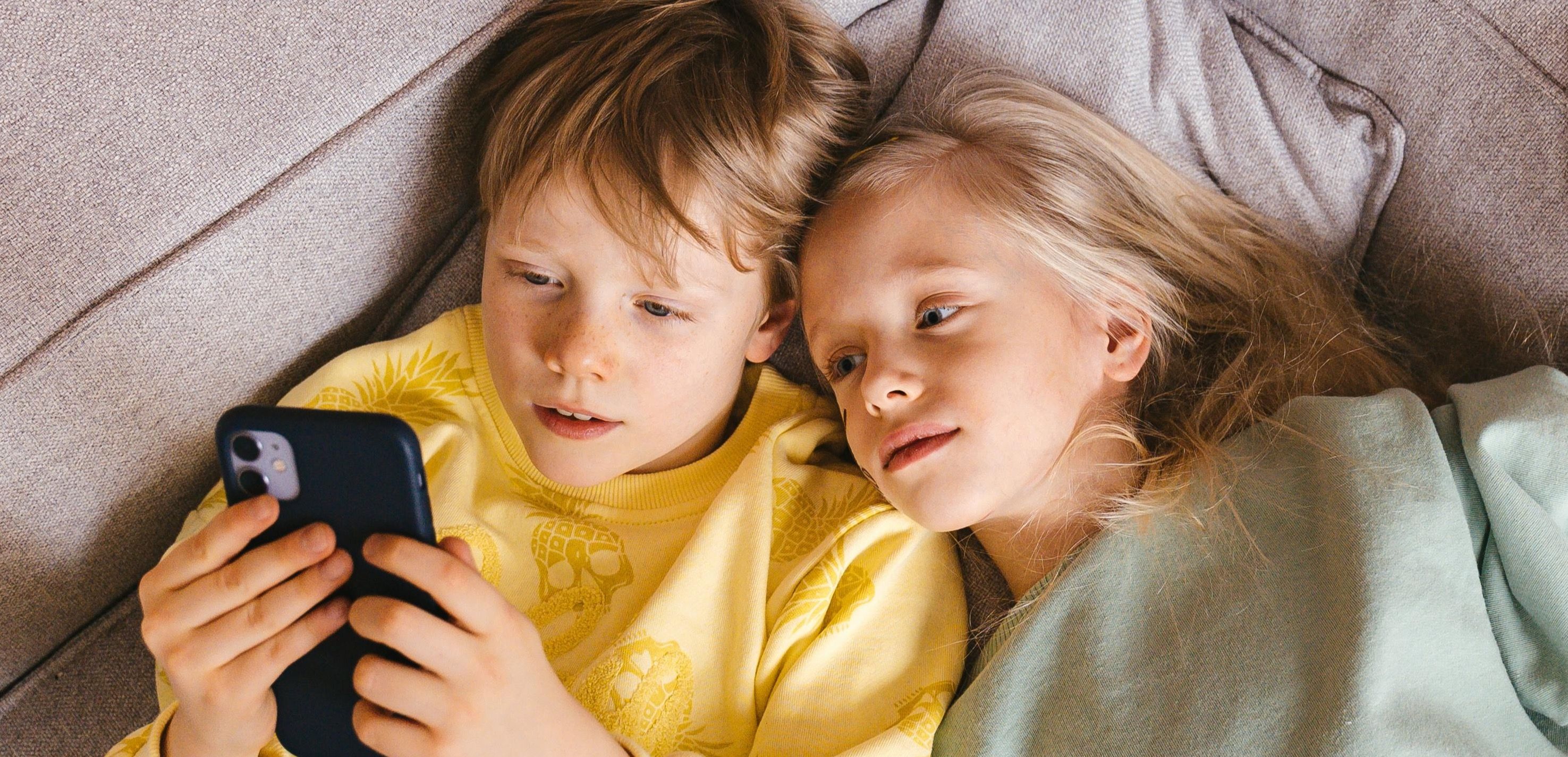 Gutt og jente med mobil som har årets beste mobilabonnement
