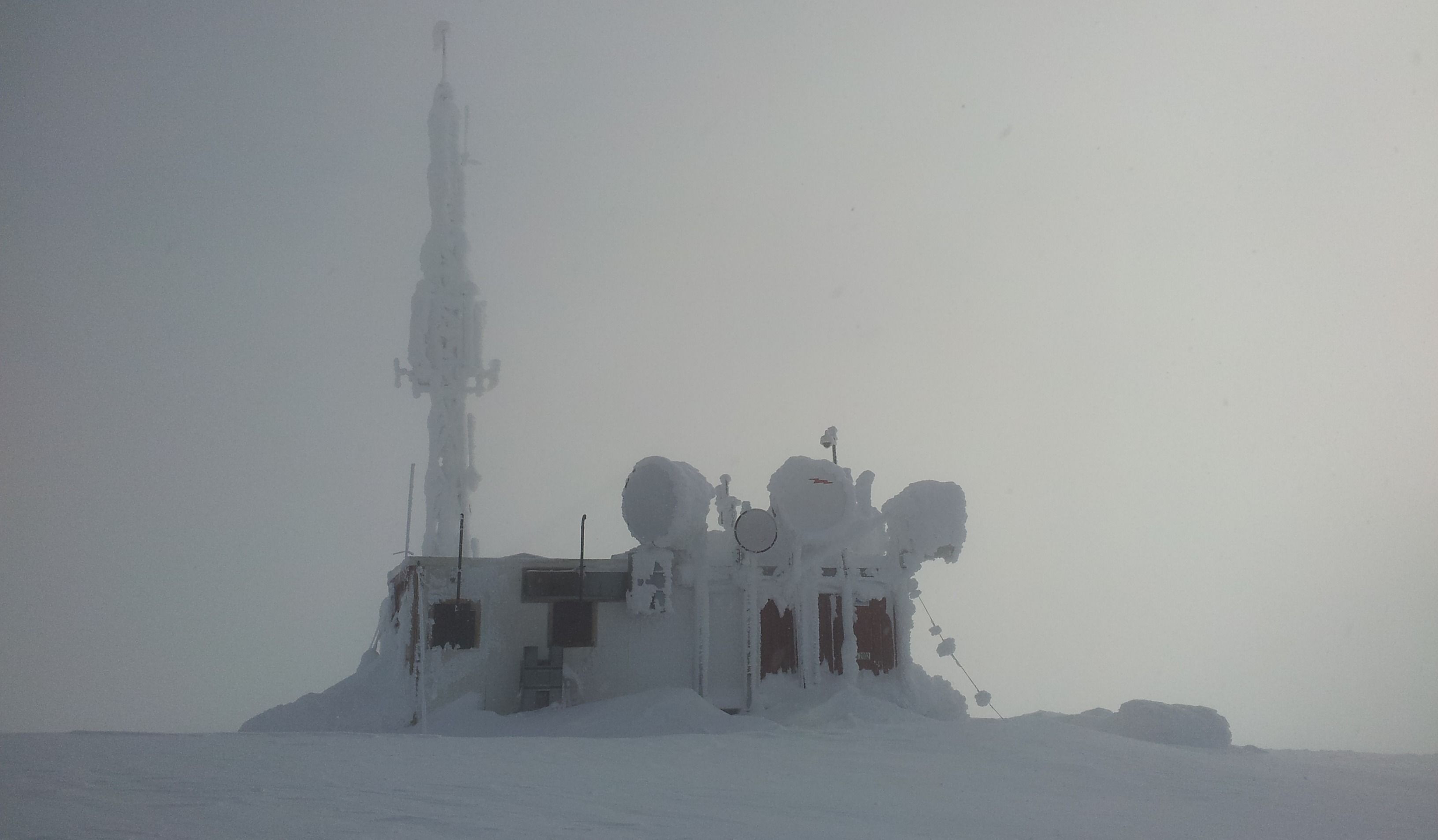 Snødekt værstasjon med antenne i tåke