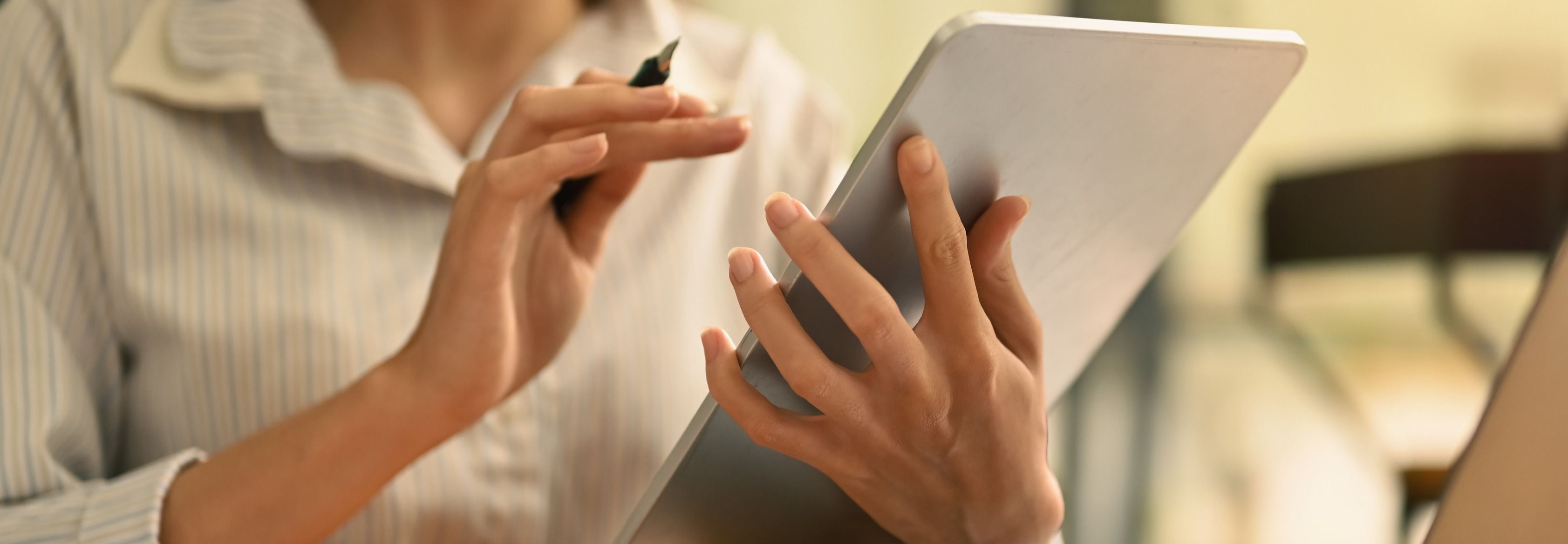 Automatiske fakturarapporter; en kvinne med en ipad i hånden og regninger på pulten