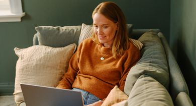 Dame i sofa ser på en laptop