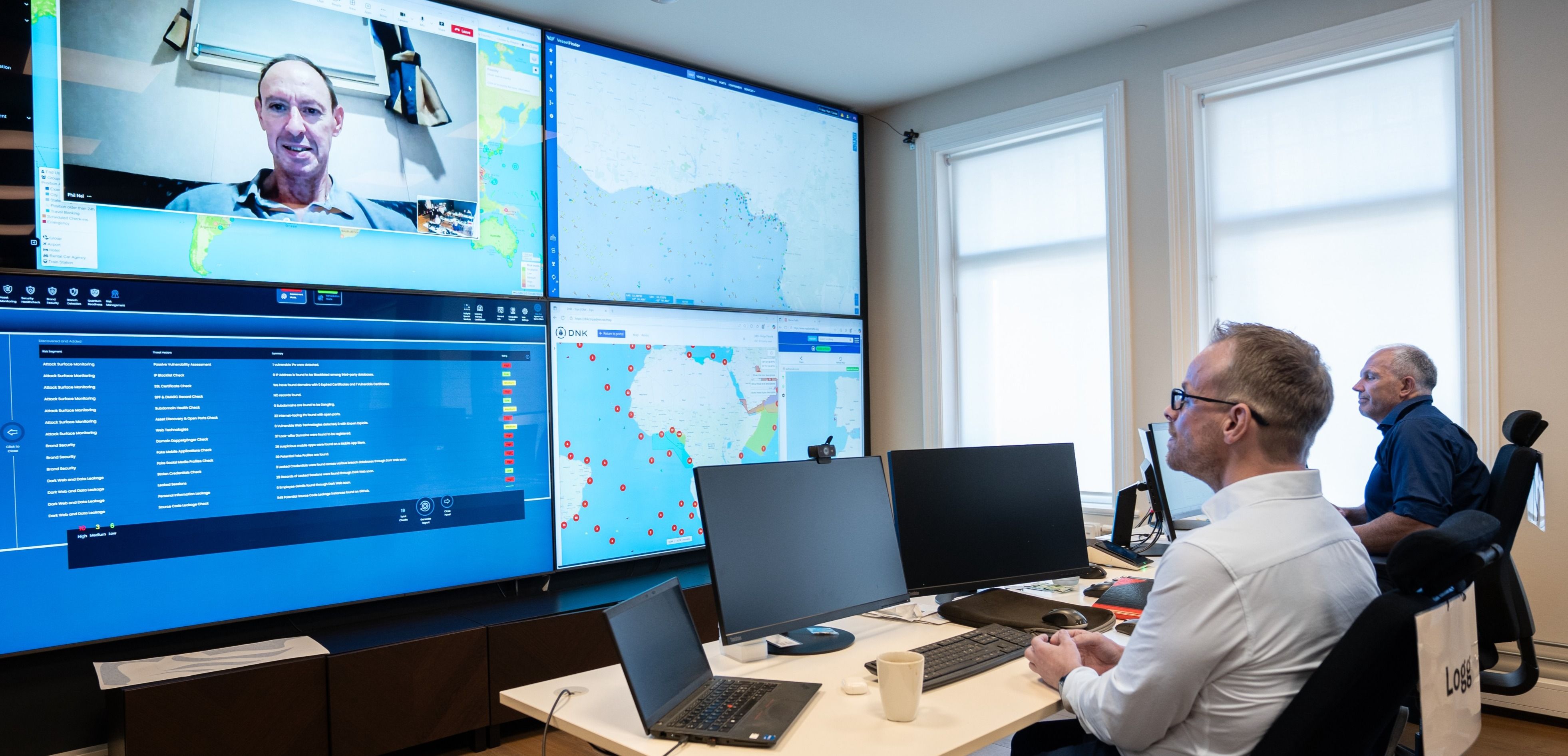 Kontrollrom med flere dataskjermer og kart på veggen