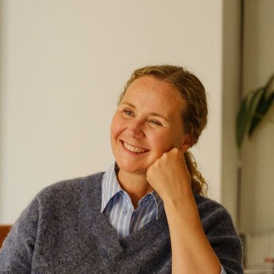 Person med blå genser og stribet skjorte sitter i tankefull stilling