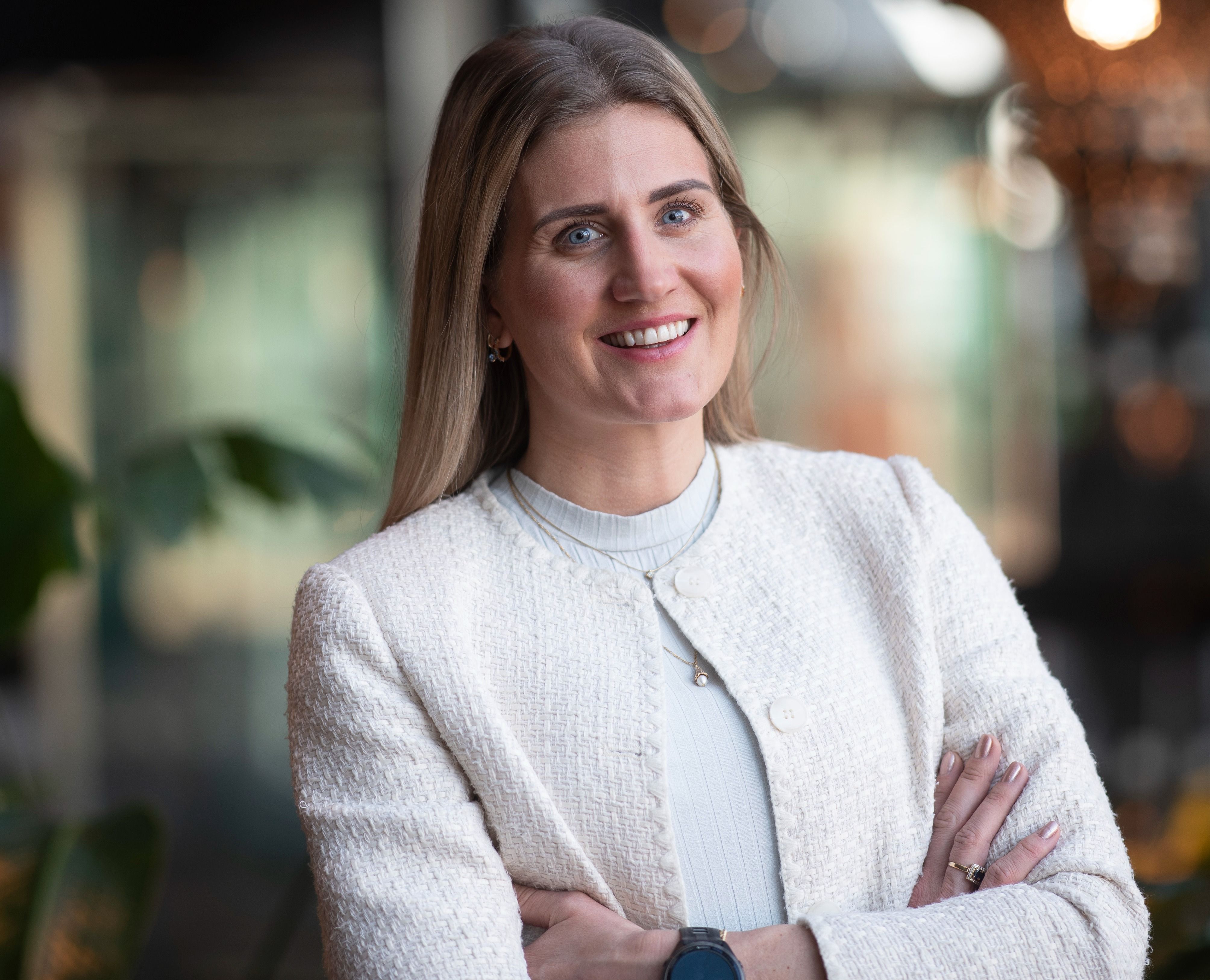 Person i hvit jakke med foldede armer, uskarp bakgrunn