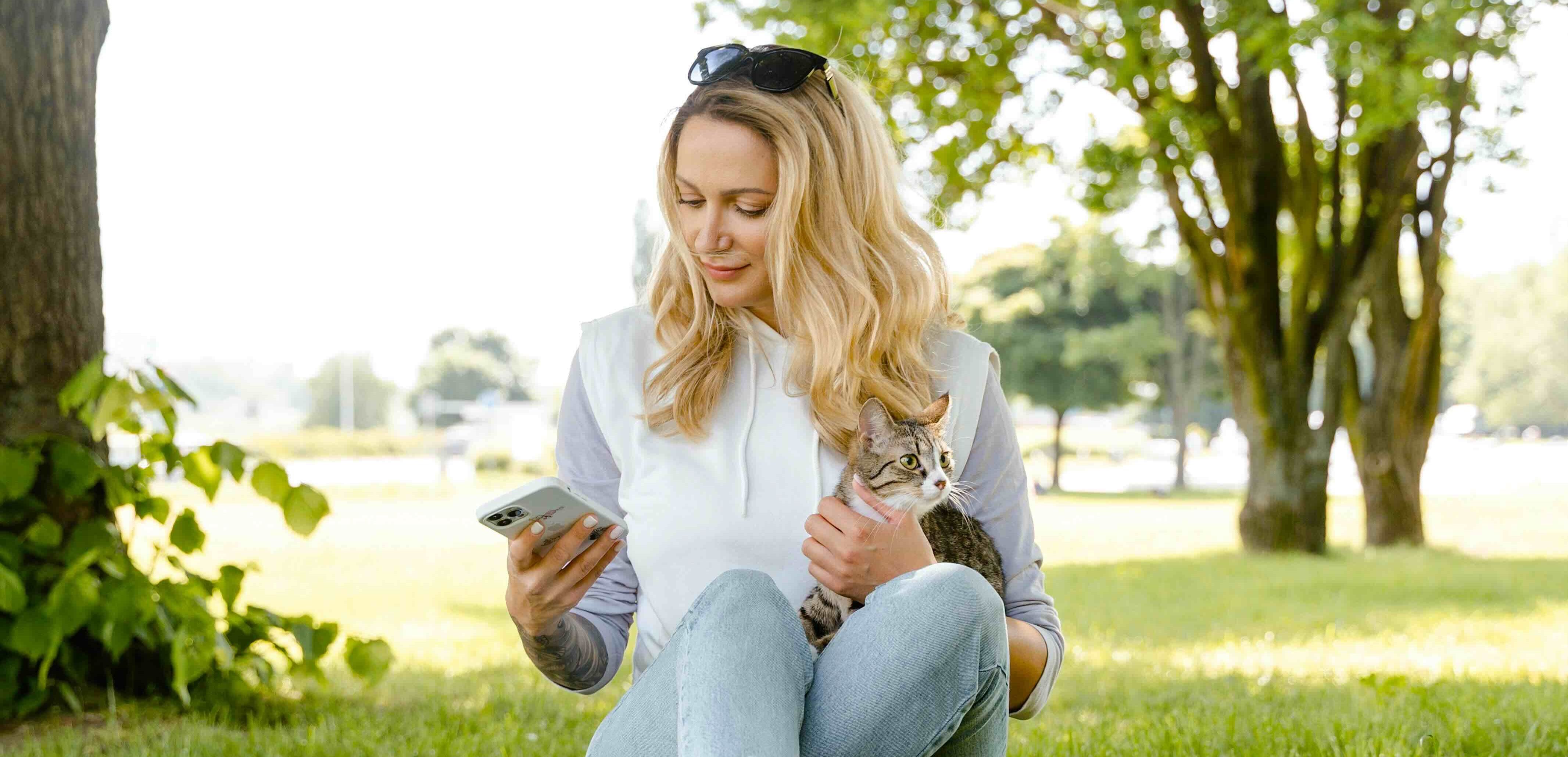 Kvinne med katt og mobil i parken