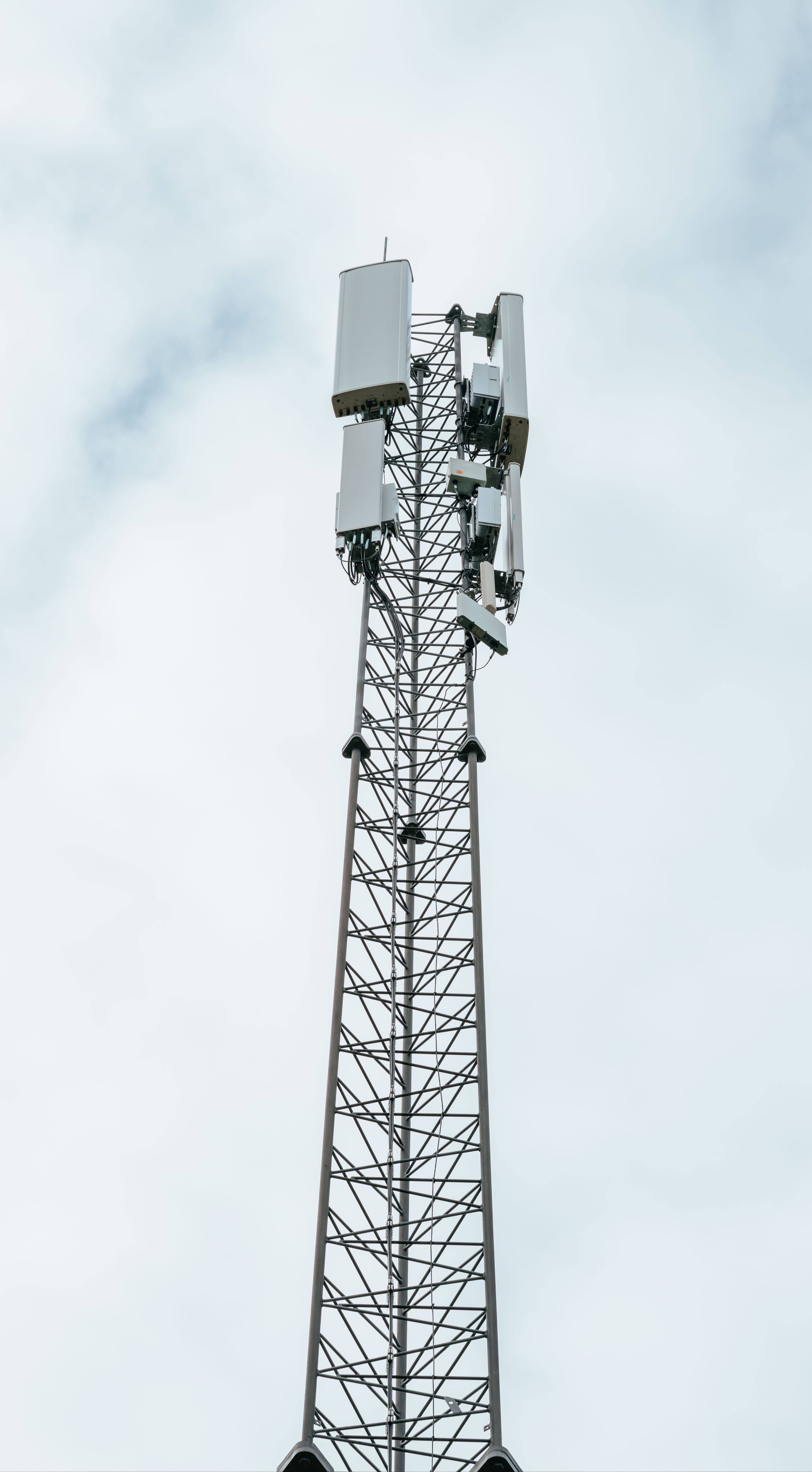 Mobilmast med flere antenner mot grå himmel