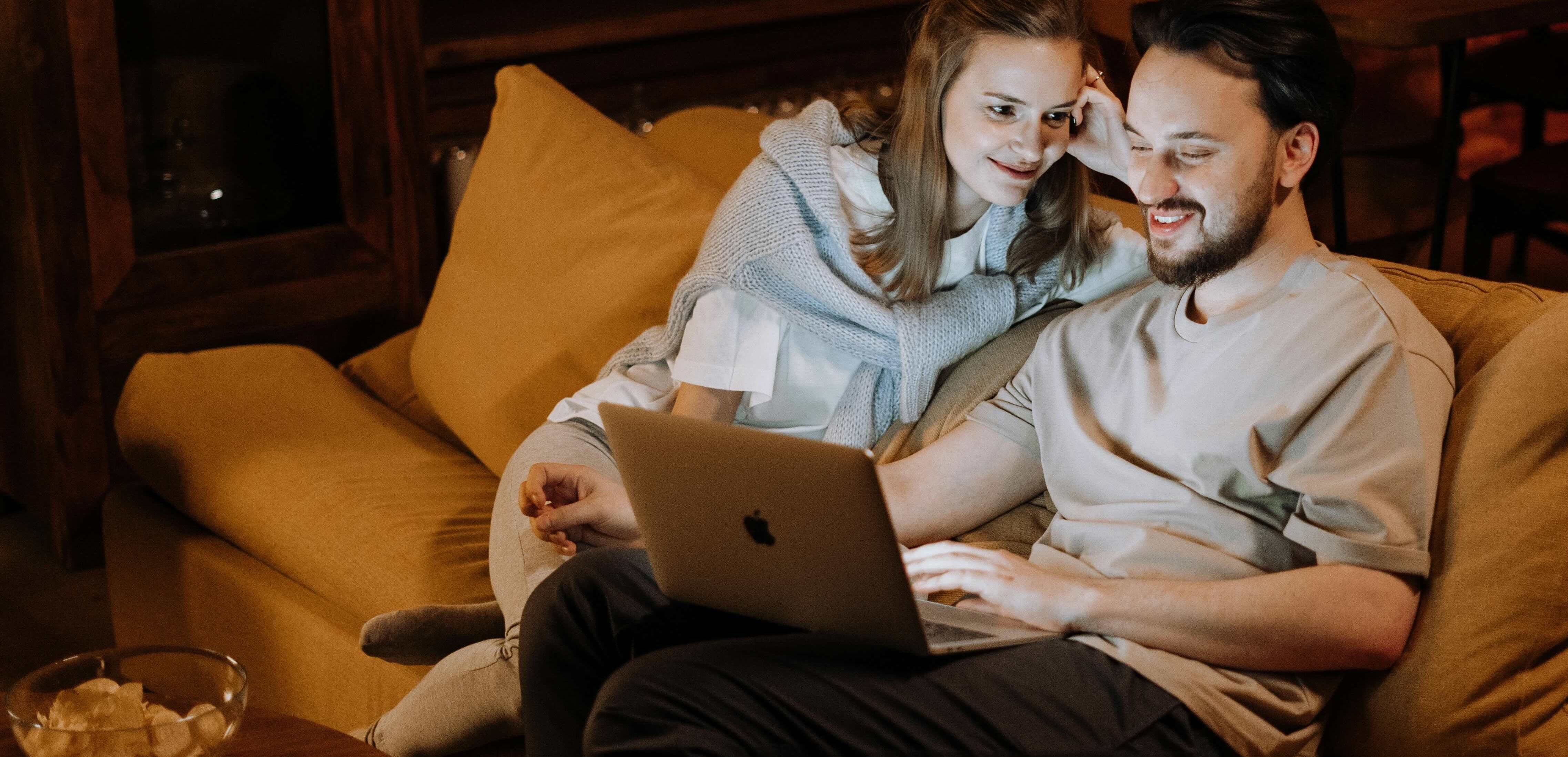 Par i sofa med laptop