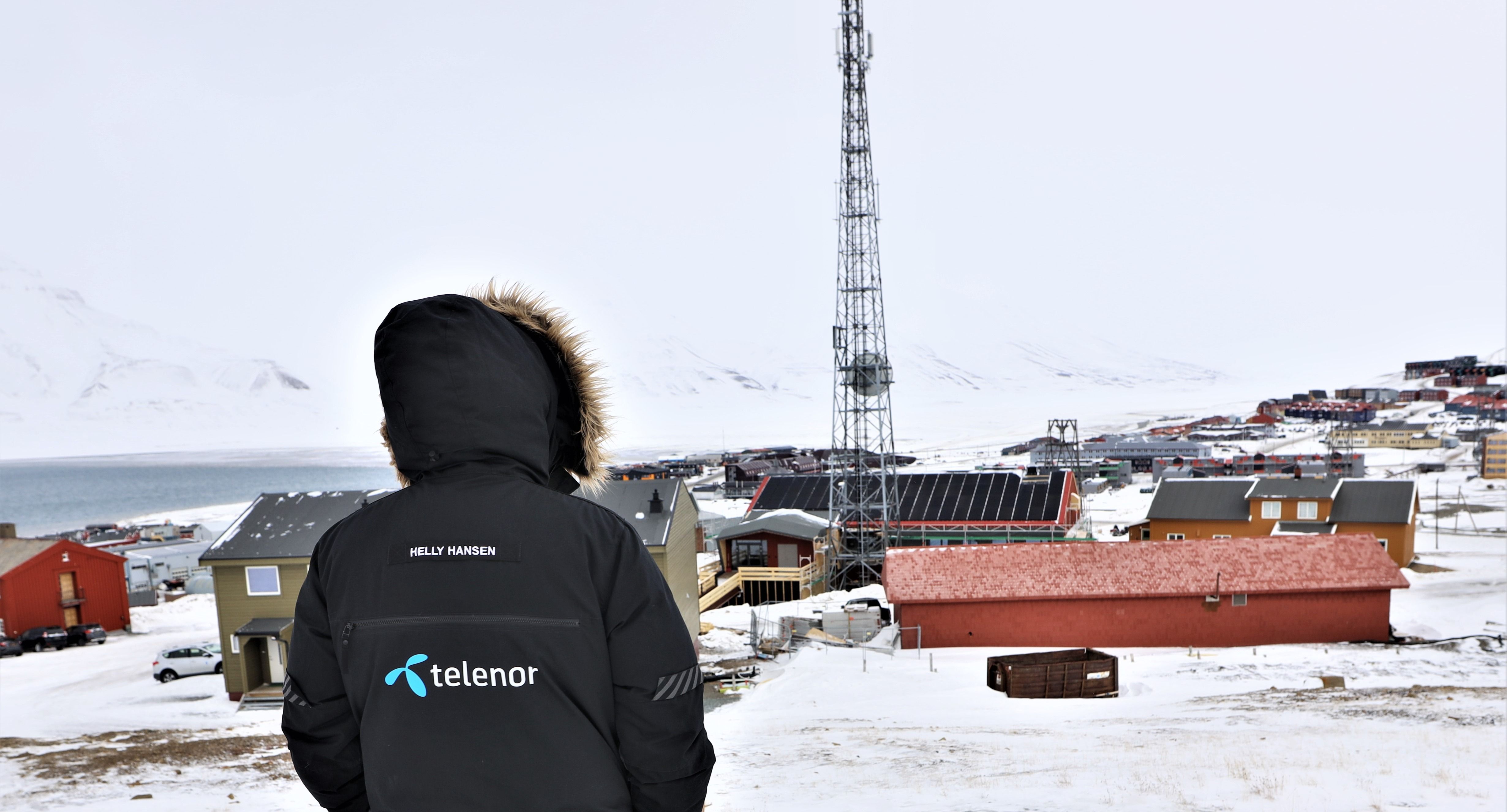 Snødekt fjelltopp med antenne og solnedgang i horisonten