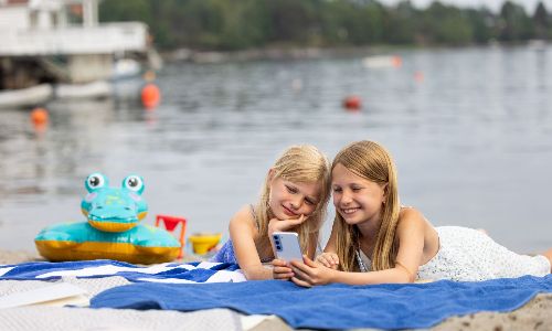 To barn på stranden som ser på mobilen