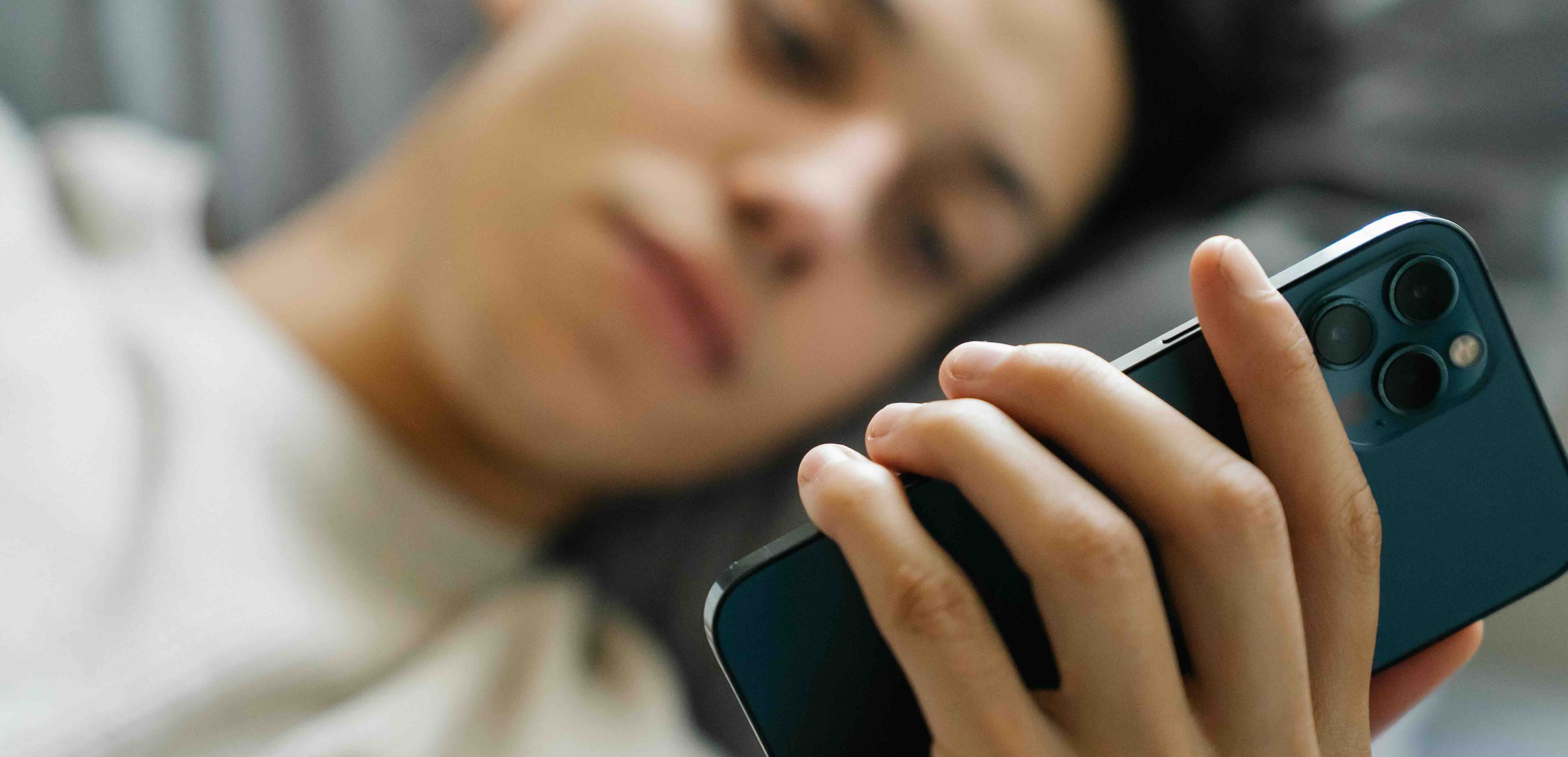 Hånd som holder en svart smarttelefon med tre kameraobjektiver