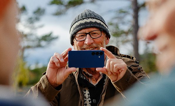 en eldre mann som tar et bilde av noen familiemedlemmer utendørs