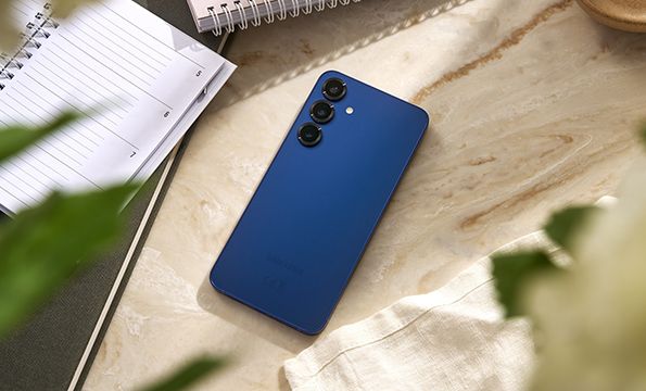 galaxy s25 i fargen navy på et marmorbord ved siden av notatbøker