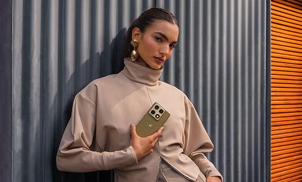 Person med beige antrekk og gulløredobber holder en motorola signature