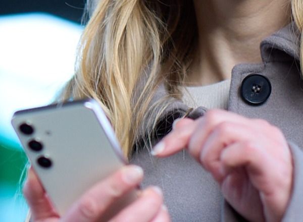 dame på toget med mobilen i hånden
