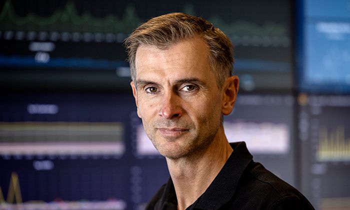 Mann med kort hår foran skjermer med grafer og data