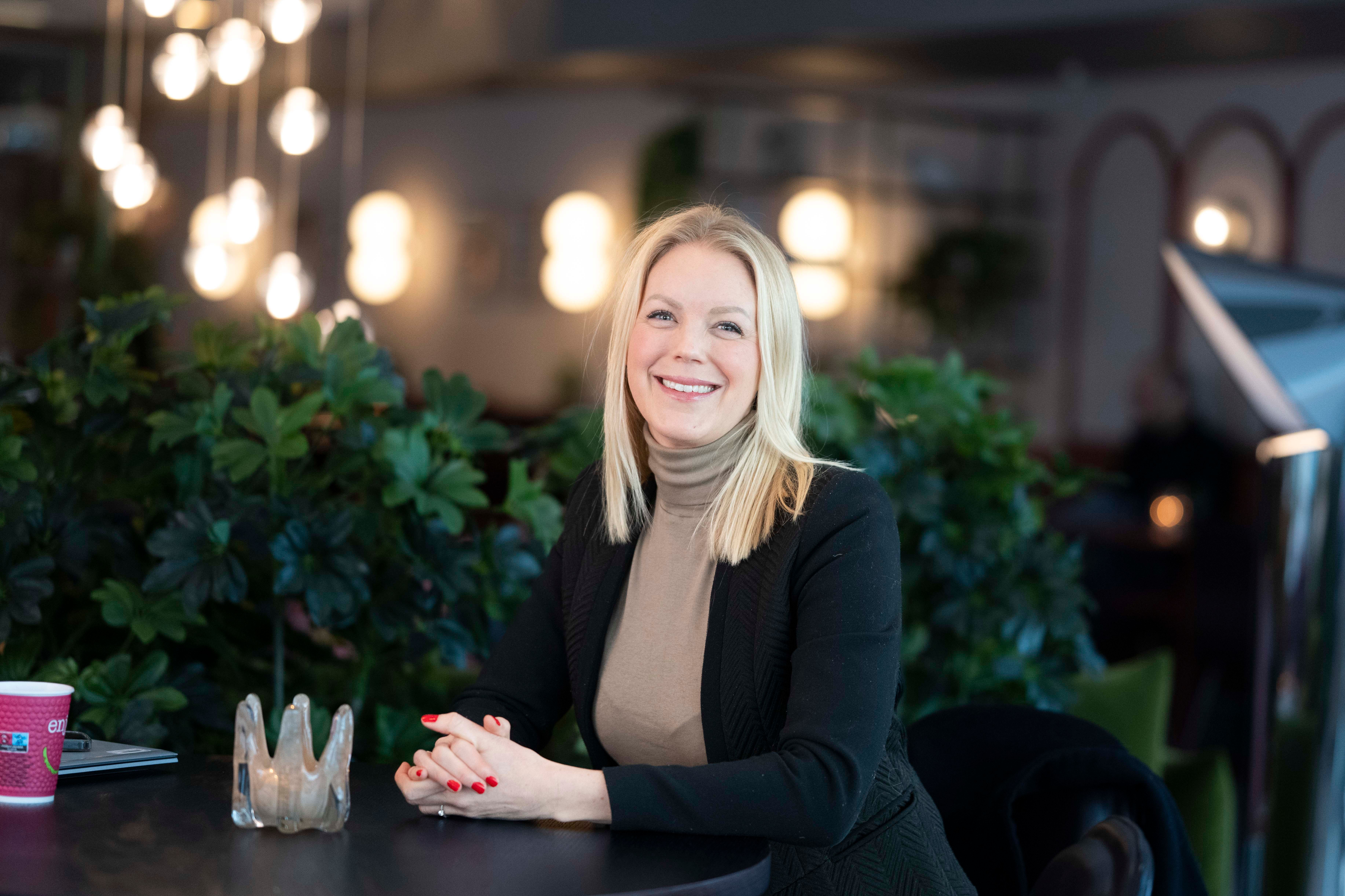 Kvinne ved bord med planter og moderne belysning i bakgrunnen