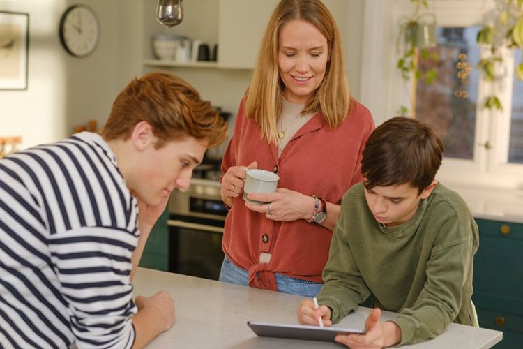 Familie samles rundt kjøkkenøy med nettbrett
