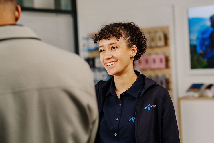 en jente som jobber i telenorbutikken smiler til en kunde