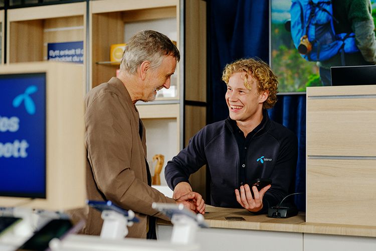 medarbeider i telenorbutikken veileder en kunde før kjøp av ny mobil