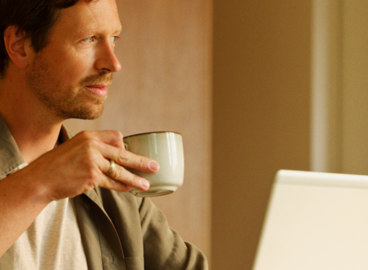 Mann med kaffekopp foran pcen