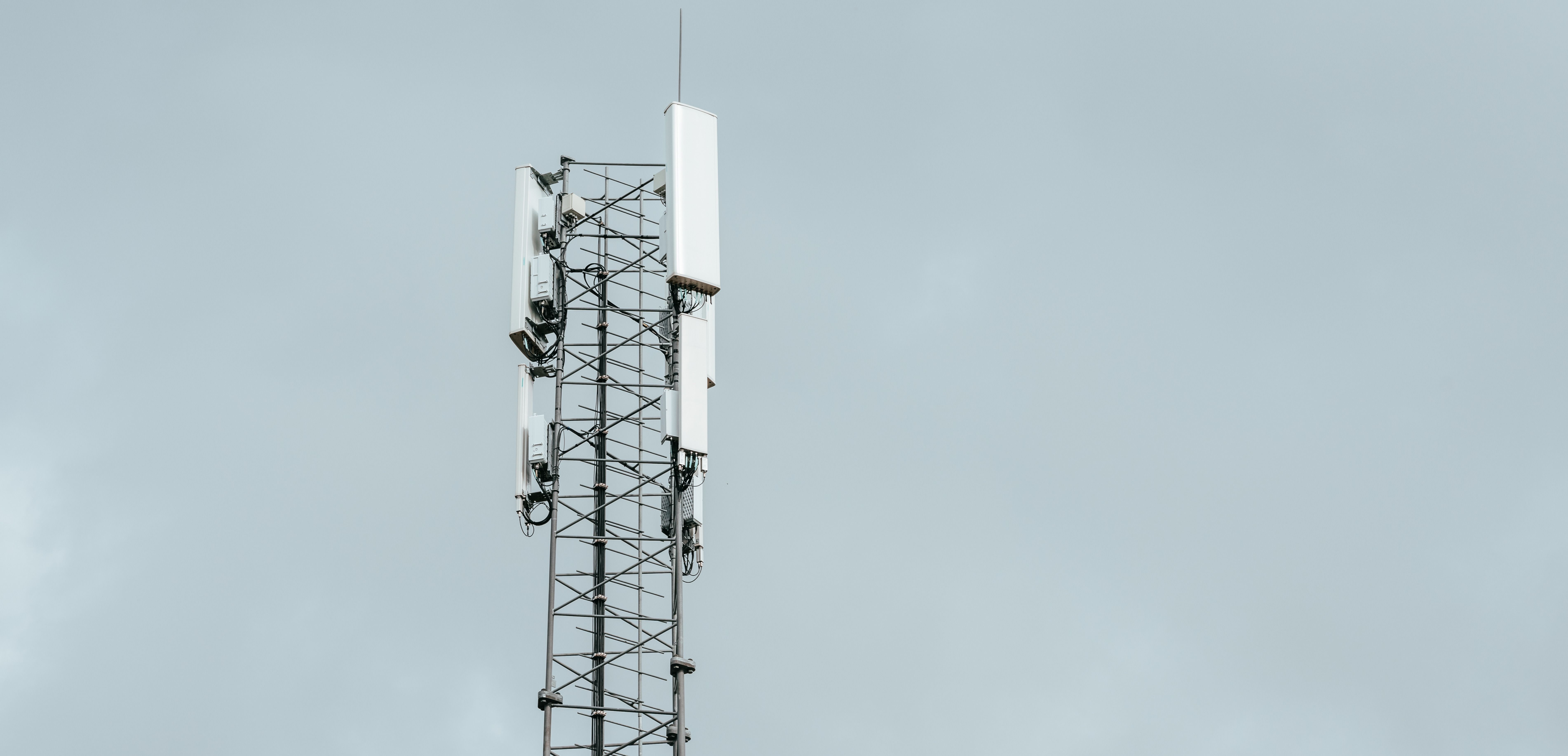 Mobilmast med antenner mot grå himmel