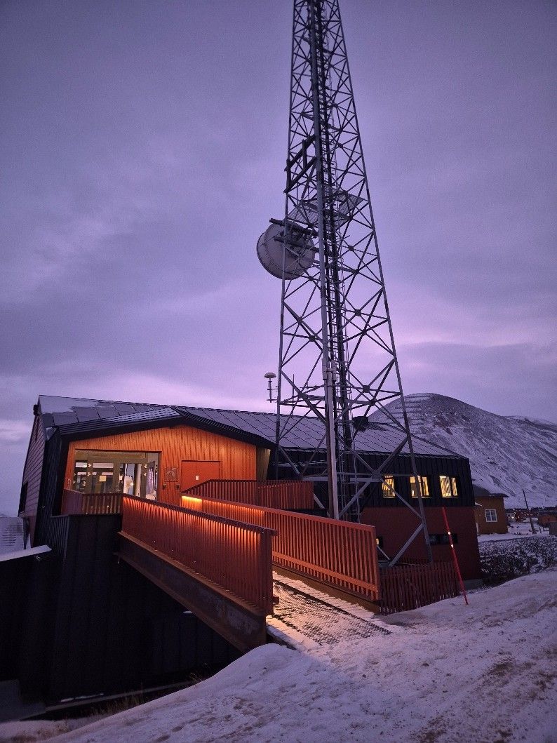 Trebygning og radiotårn i arktisk vinterlandskap på Svalbard