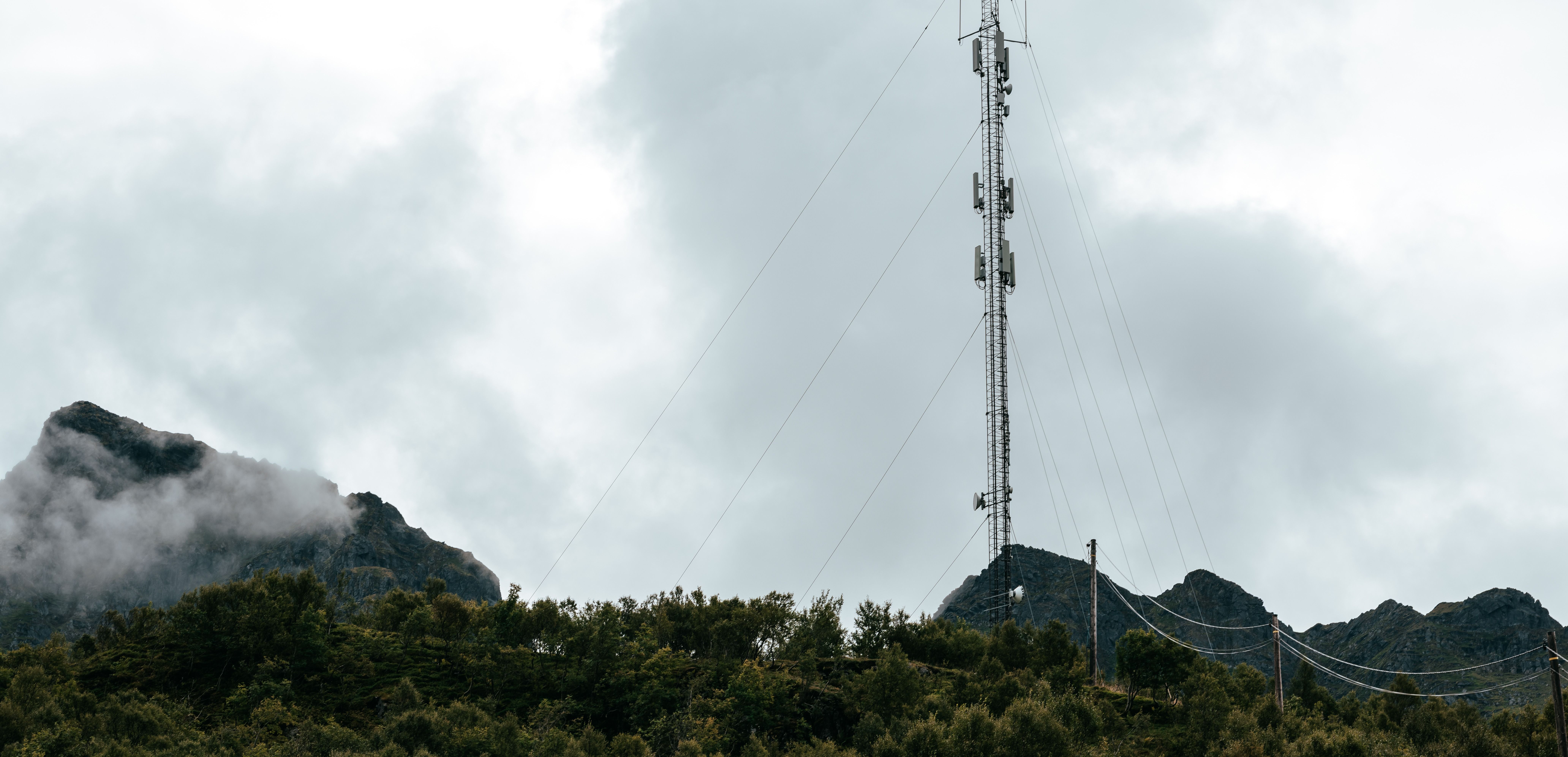 En telekommunikasjonsmast omgitt av fjell og skyer