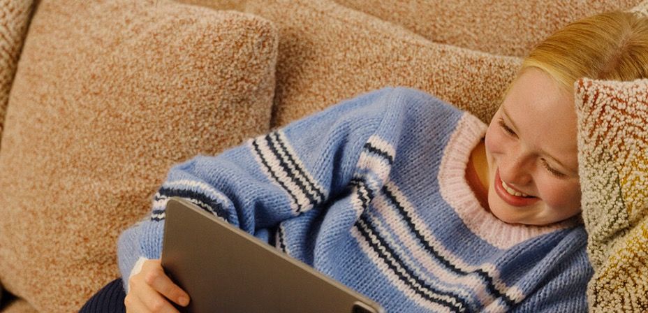 Jente ser på Ipad i sofaen