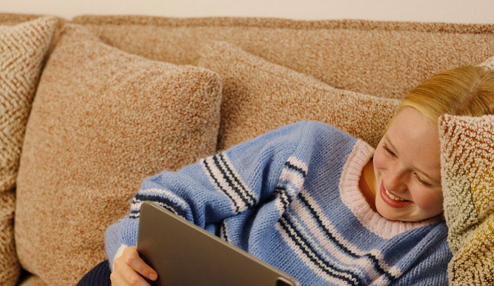 Jente ser på Ipad i sofaen