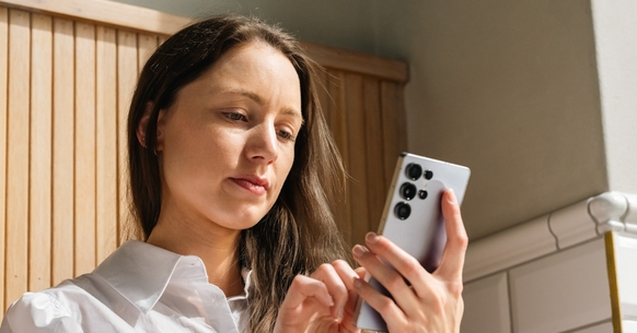Dame i hvit skjorte holder i en mobil
