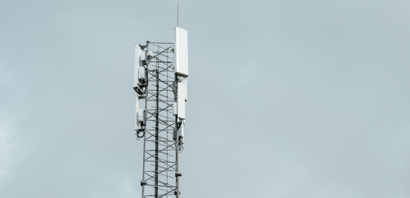 Mobilmast med antenner mot grå himmel