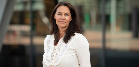 Kvinne i hvit bluse foran bygning