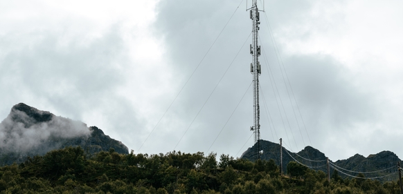 En telekommunikasjonsmast omgitt av fjell og skyer