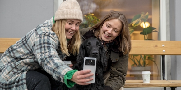 Data skylagring: To venninner bruker mobilen for å laste opp bilder og video til skyen