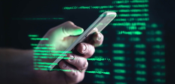 Hånd holder en mobiltelefon med grønn digital tekst i bakgrunnen