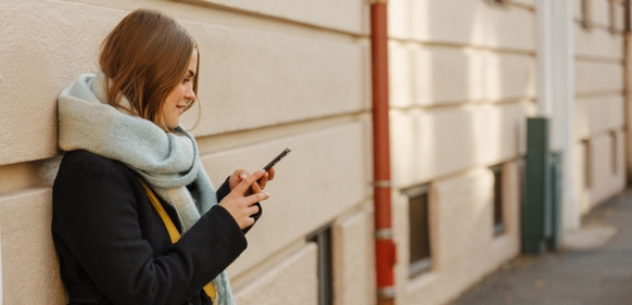 Kvinne med Telenor-trygghet ser på mobil ved vegg